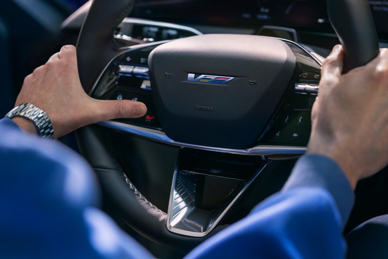 Close-up of a Man About to Press the V-Button on the 2026 OPTIQ-V Steering Wheel | Jerry's Cadillac in Weatherford TX