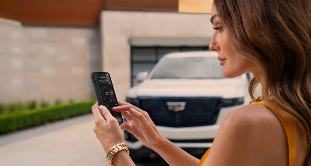 lady checking her mobile with a Cadillac vehicle background | Jerry's Cadillac in Weatherford TX